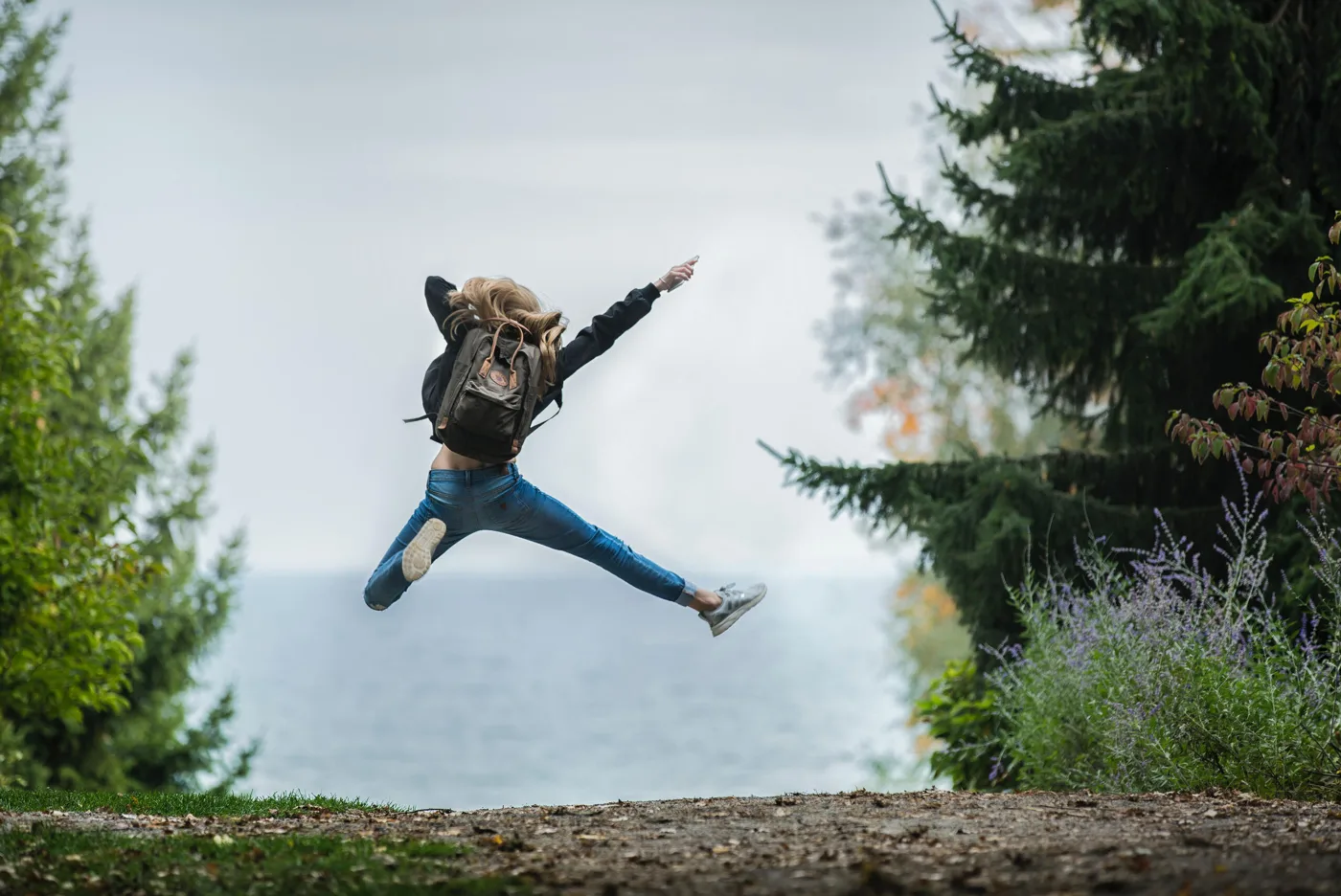 Ein Mensch springt voller Leichtigkeit auf einem Weg in der Natur, Weite im Hintergrund