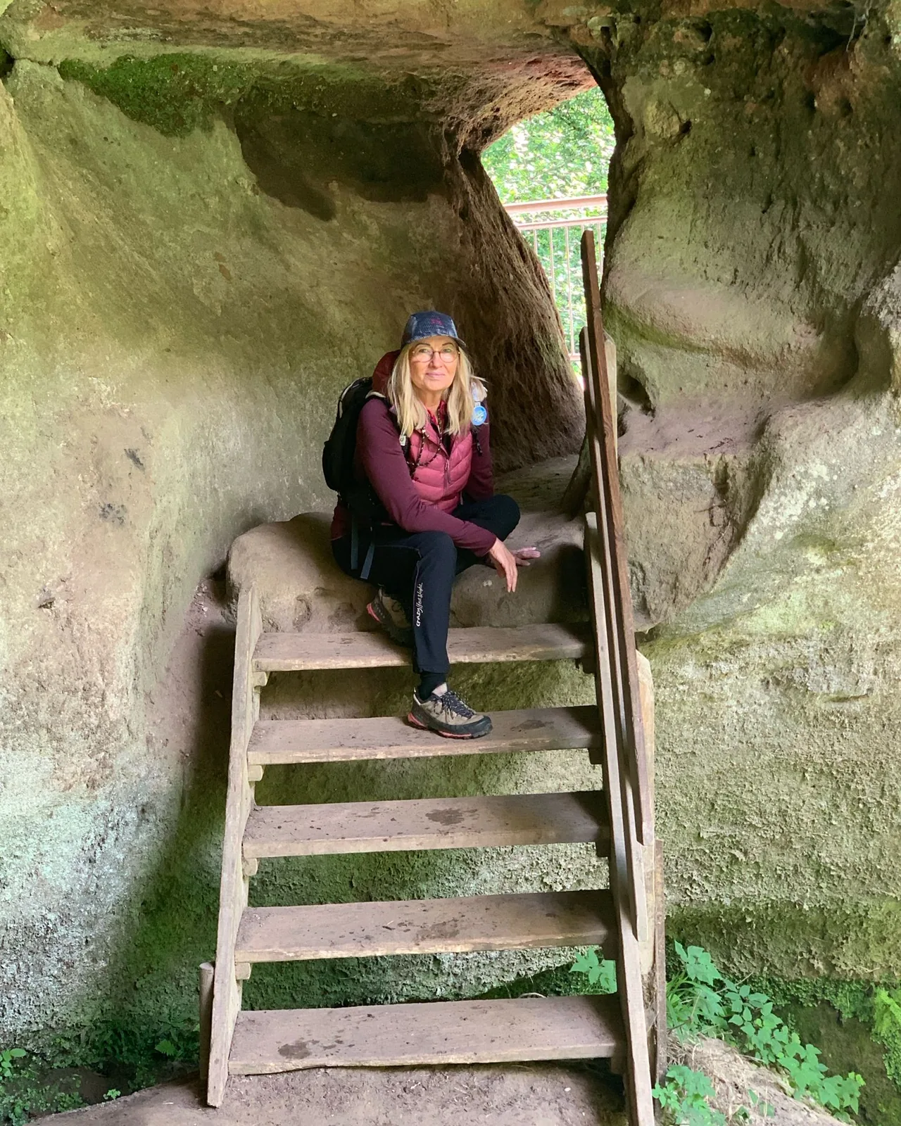 Sabine Rößler macht Rast auf einer Holztreppe in einem Felsen