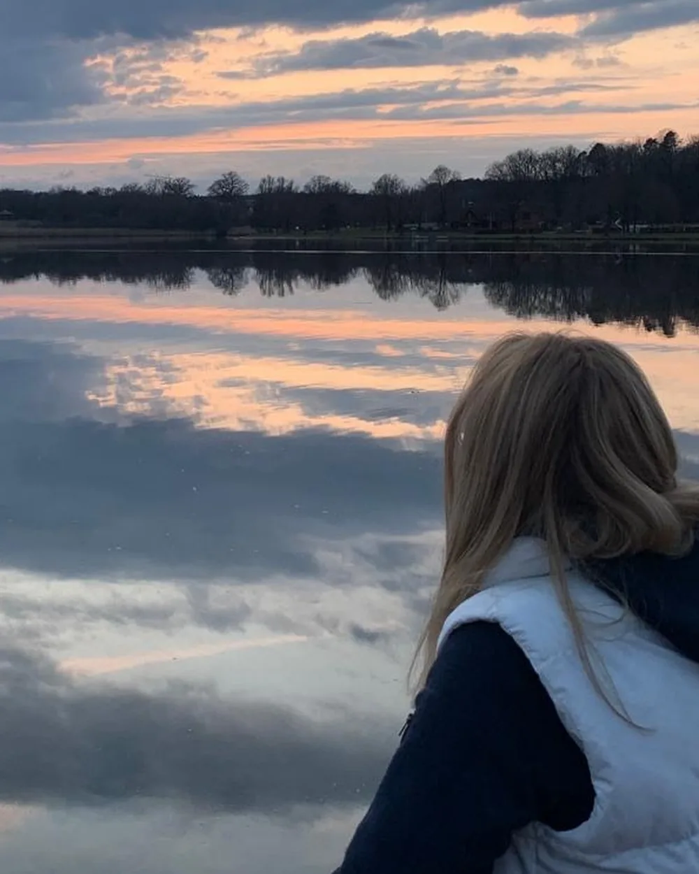 Sabine Rößler blickt am ruhigen See auf das Wasser im Abendlicht
